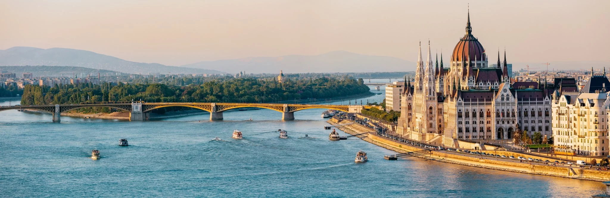 Panoramic view of Budapest, Hungary featuring the Hungarian Parliament Building and the Danube River.